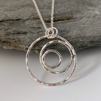 A silver pendant made from three hammered silver wire circles of different sizes soldered inside each other in an off centre design.