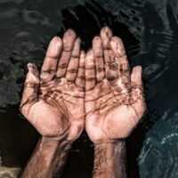 From above of crop anonymous male washing hands in clean water of lake in daytime