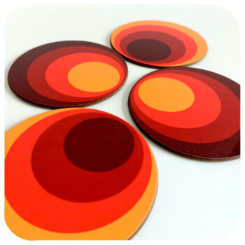 four 70s style round coasters in orange and brown on a white background