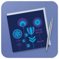 Scandi style retro flowers greetings card in blue and purple on a lilac background with white envelope and silver pen